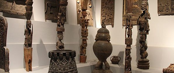 A diverse collection of African art pieces including sculptures, pottery, and reliefs.