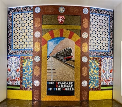 Joyce Kozloff's 1985 glass mosaic and tile mural at Philadelphia's Suburban Station celebrates the city's role as a transportation hub, combining imagery of a speeding train inspired by Fix-Masseau's 1929 <i>Orient Express</i> poster with decorative motifs and an archway drawn from Istanbul's Topkapi Palace.